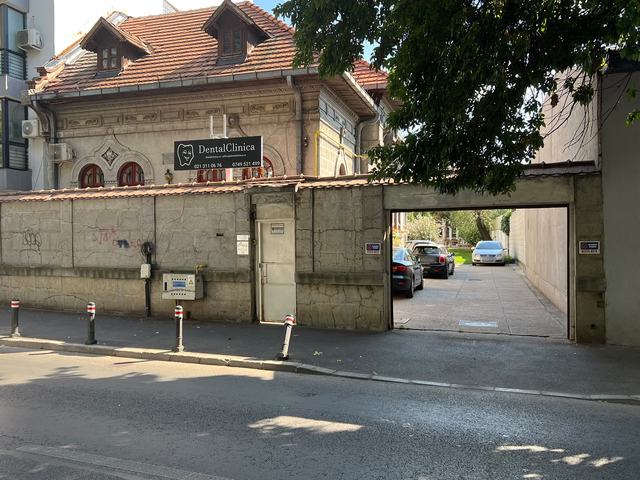 DentalClinica văzută din Strada Matei Voievod: casa cu acoperiș de țiglă, firma neagră DentalClinica și poarta de acces în curte