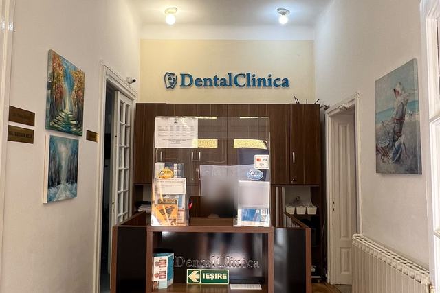 Recepția DentalClinica: biroul de primire, cu numele clinicii pe perete și tablouri