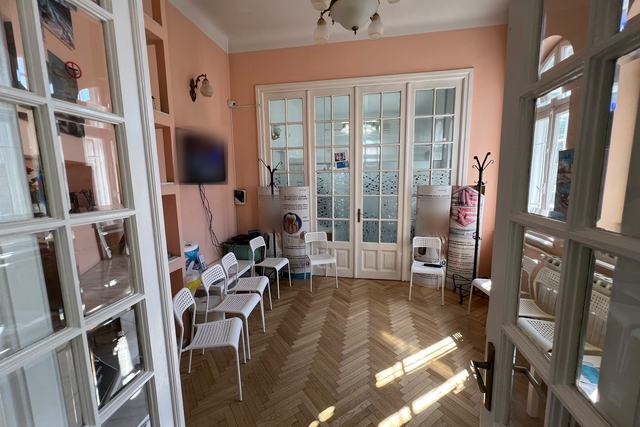 Sala de așteptare DentalClinica: pereți în nuanțe calde, candelabru, parchet în spic și uși albe cu geam